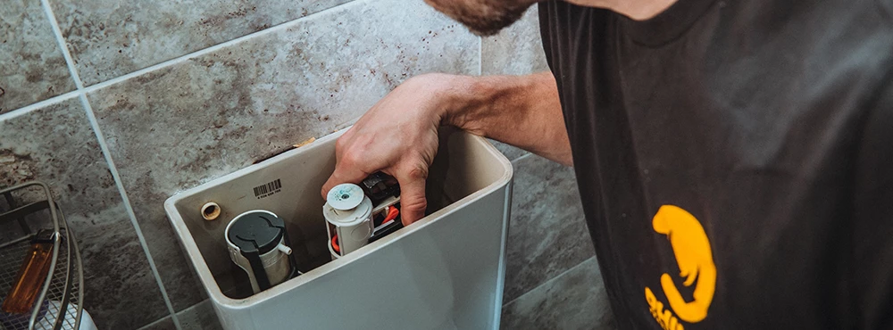 Man wearing Rhino Trade Insurance t-shirt fixing the toilet bowl