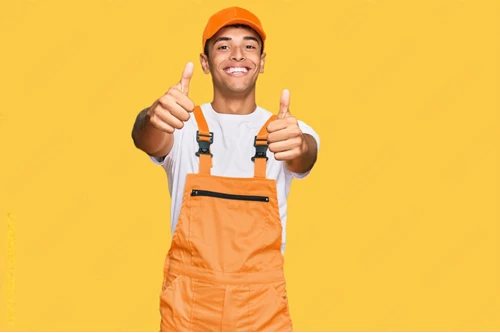 Young man wearing handyman uniform approving doing positive gesture with hand